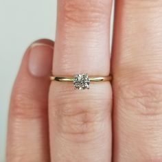 a close up of a person's hand with a diamond ring on their finger