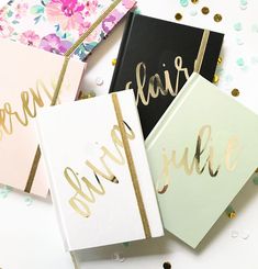 four cards with gold foil lettering on them and some confetti in the background