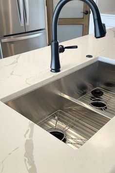 white quartz countertops with stainless steel undermount sink installed with matte black faucet and garbage disposal button Kitchen Sink Install, Village Home, Engineered Quartz, Countertop Surfaces, Steel Kitchen Sink, Cultured Marble, Marble Vanity Tops