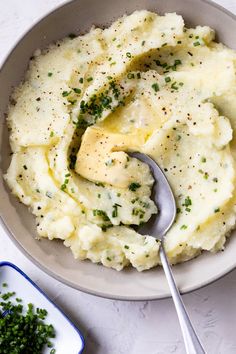 mashed potatoes with butter and parsley in a bowl next to a serving spoon