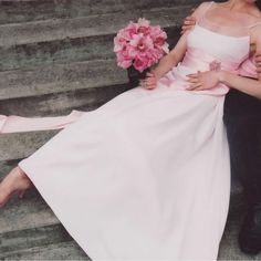 a man and woman are sitting on the steps with their arms around each other while holding flowers