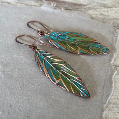 These hand painted artsy copper leaf earrings are a unique and striking accessory that have been crafted in our island studio using a special house patina paint blend resulting in a beautiful blue green finish reminiscent of the Caribbean sea. Once the patina process is complete, we buff and seal the copper for durability and to prevent tarnishing. Each pair of earrings are one-of-a-kind, with variations in the patina that add to their handmade charm. Size: 2.50 Inches from Lobe Ear Wire: Choice of Antique Copper or Sterling Silver French Ear Hooks with Safety Back Lightweight and Comfortable Handmade in the USA Gift Ready: Your earrings come in a gift pouch ready for giving or to treasure for yourself. Artistic Hand Painted Copper Earrings, Hand Painted Copper Bohemian Earrings, Hand Painted Copper Artsy Earrings, Hand Painted Artsy Copper Earrings, Artsy Hand Painted Copper Earrings, Bohemian Hand Painted Copper Earrings, Artsy Hand Painted Copper Jewelry, Green Hand Painted Copper Earrings, Hand Painted Green Copper Jewelry