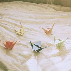 four origami birds sitting on top of a bed