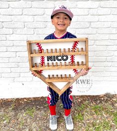 a young boy holding up a wooden baseball game