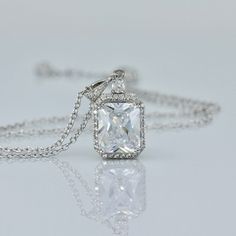 "Classically elegant and sophisticated! Emilia cz crystal bridal necklace made in a radiant cut with a frame of tiny cz crystals for a beautiful sparkling accessory that will suit your dress, whatever style. The 18K rhodium setting has delicate carving around the sides so your necklace is pretty from all aspects! All components are rhodium plated sterling silver. Nickel free. Rhodium plating helps prevent issues with silver allergies. Measurements: Chain - With extender measures 16\" - 18\" (41 Luxury Square Pendant Solitaire Necklace For Gift, Classic Wedding Jewelry With Rectangular Pendant, White Gold Rectangular Pendant For Wedding, Elegant Diamond Rectangular Necklace, Elegant Rectangular Diamond Necklace, Dazzling Emerald-cut Cubic Zirconia Necklaces, Dazzling Emerald Cut Cubic Zirconia Necklaces, Wedding Jewelry With Square Cut Halo Setting, Dazzling Emerald Cut Cubic Zirconia Necklace