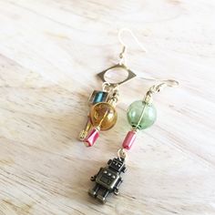 A pair of asymmetrical robot and glass dome earrings Dome Earrings, Asymmetrical Earrings, Earrings Beaded, Gold Colour, Glass Dome, Jewelry Designer, Glass Domes, Earrings Gold, Beaded Earrings