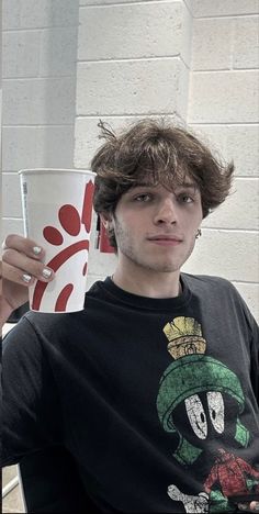 a young man is holding up a cup