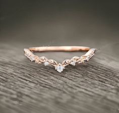 a rose gold wedding band with three diamonds on the top and an arrow design in the middle