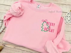 Merry & Bright Christmas Embroidered Sweatshirt Celebrate the season with this festive embroidered sweatshirt.    Enjoy a classic soft sweatshirt that's custom embroidered for you. The shirt is medium-weight, making it perfect for cool fall evenings and crisp winter days. You can't go wrong with a new favorite sweatshirt to complement a comfy pair of jeans. Each shirt is custom-made with care for you at the time your order is placed. Only quality shirts and materials are used. I primarily use JERZEES brand shirts, but on occasion, due to inventory, I may have to use a comparable brand if my supplier is out of the color or size you have selected. Shirt Details:  Adult/Unisex sizes. Medium weight 8 oz. 50/50 cotton/polyester NuBlend® pill-resistant fleece A sizing chart is available in the l Embroidered Cotton Christmas Sweatshirt, Winter Gift Tops With Embroidered Logo, Casual Christmas Sweatshirt With Custom Embroidery, Winter Tops With Embroidered Logo For Gifts, Winter Pink Sweatshirt With Embroidered Graphics, Winter Tops With Embroidered Logo As Gift, Pink Winter Sweatshirt With Embroidered Graphics, Casual Embroidered Sweatshirt For Holiday, Christmas Cotton Sweatshirt With Embroidered Logo