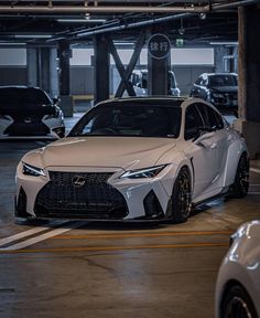 a white sports car parked in a parking garage next to other cars on the street