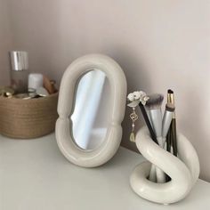 there is a mirror and some makeup brushes on the counter in front of a vase