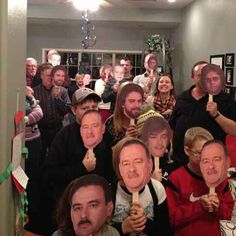 a group of people standing around each other in a room with christmas decorations on the walls