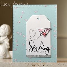 a close up of a small card with a paper airplane on it and the tag says sending lots of love