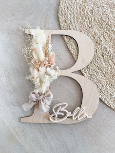 a wooden sign with the letter b on it sitting next to a hat and rug