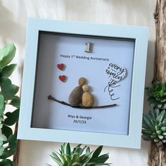 two rocks sitting on top of a tree branch in a shadow box with the words happy 1st wedding anniversary