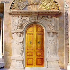 an ornate building with two doors and statues on the front door, one is yellow