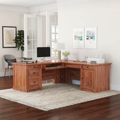 a wooden desk sitting on top of a hard wood floor next to a white wall