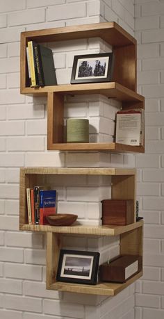 three wooden shelves with books on them against a white brick wall