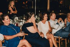 a group of people sitting next to each other at a dinner table with drinks in front of them