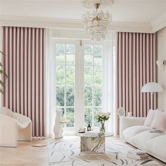 a living room filled with furniture and a chandelier hanging from the side of a window