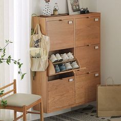 a wooden cabinet filled with lots of shoes next to a chair and bag on the floor