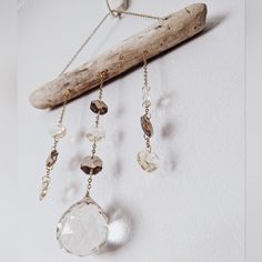 a piece of driftwood is hanging on the wall with beads and chains attached to it