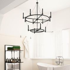 a white bath tub sitting under a chandelier in a bathroom