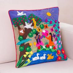 a decorative pillow is sitting on a white couch in front of a wall with flowers and birds