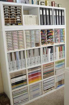 a white bookcase filled with lots of books and binders on top of it