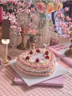 a heart shaped cake sitting on top of a table next to candles and vases