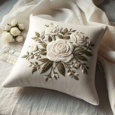 a white pillow sitting on top of a bed next to a lace doily and flowers