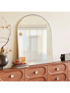 a dresser with a mirror and vase on it