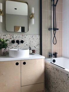 a bathroom with a sink, mirror and bathtub next to a shower head mounted on the wall