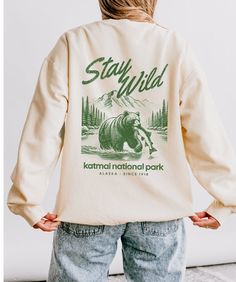 🌲✨ Whether you're hiking through lush forests or dreaming of your next national park adventure, our "Stay Wild" crewneck is here to keep your spirit cozy and your style on point. Inspired by the raw beauty of Katmai National Park, Alaska, this lightweight Comfort Colors crewneck features a retro-inspired font that reads "STAY WILD" and a majestic bear in a stream, proudly holding its catch of the day. Underneath the bear, you'll find "Katmai National Park, Alaska" as a tribute to one of the most breathtaking spots on Earth. This crewneck is perfect for older teens and young adults who love traveling, the outdoors, and embracing the granola girl aesthetic. Made from 100% ring spun cotton, it promises that soft, lived-in feel from day one. Throw it on for your next camping trip, or just roc Casual Sweatshirt With Letter Print For Outdoor Activities, Casual Sweatshirt With Letter Print For Outdoor, Casual Letter Print Sweatshirt For Outdoor Activities, Casual Winter Hiking Tops, Casual Crew Neck Sweatshirt For Adventure, Fall Hiking Sweatshirt With Letter Print, Casual Hiking Sweatshirt With Letter Print, Casual Letter Print Sweatshirt For Hiking, Casual Fall Hiking Tops