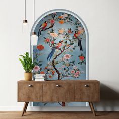 a blue wall with flowers and birds painted on it, next to a wooden cabinet