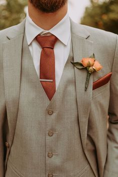 a man wearing a suit and tie with an orange boutonniere on his lapel