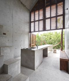 an empty concrete room with stairs leading up to the second floor and windows above it