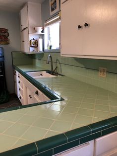 a kitchen with green counter tops and white cabinets in the back drop off cabinetry