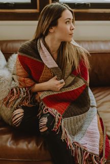 a woman sitting on a couch wrapped in a blanket