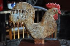 a rusty rooster statue sitting on top of a wooden table