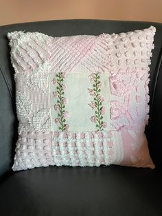 a pink and white pillow sitting on top of a black chair