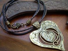 a heart shaped pendant sitting on top of a wooden table next to an old knife