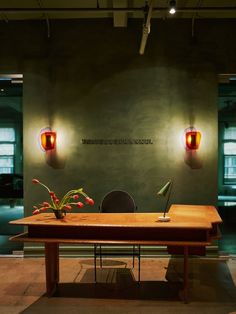 a wooden table topped with a vase filled with flowers next to two red light bulbs