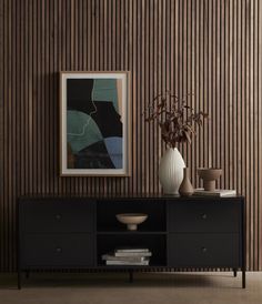 a vase with some flowers on top of a black cabinet in front of a striped wall