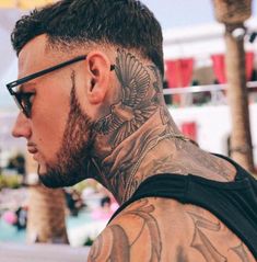 a man with tattoos on his neck and shoulder is looking at something in the distance