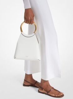 Exquisitely crafted in Italy from supple leather, the Ursula tote delivers luxury and versatility in a small package. New for Spring/Summer 2024, this style is designed in a sleek, minimalist silhouette and artfully finished with a gilded ring top handle. It looks just as chic with a daytime sundress as it does with a pantsuit after dark. Michael Kors White Tote Shoulder Bag, Modern Shoulder Tote Bag With Silver-tone Hardware, Michael Kors Leather Shoulder Bag With Silver-tone Hardware, Convertible Crossbody Bag, Purse Brands, Leather Ring, Small Tote Bag, Michael Kors Collection, Small Tote