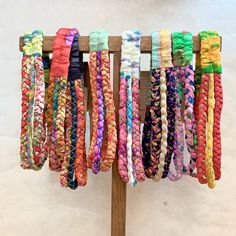 colorful bracelets are hanging on a wooden rack