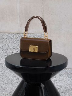 This product is made with at least 20% sustainable materials by weight. CHARLES & KEITH uses recycled, degradable, organic, and water-based materials in our eco-conscious collection. This timeless dark brown version of our metallic turn-lock bag is an investment piece that you can carry for all occasions. Featuring gold-toned hardware and a metallic turn-lock closure that opens up into a surprisingly spacious interior, this classy and compact piece can hold all your must-have items with ease. Carry yours by the top handle, or simply clip on the adjustable strap to turn it into a crossbody bag so you can go hands-free. Charles And Keith Bags, Minimalist Bags, Charles And Keith, Minimalist Bag, Size Chart For Kids, Classic Bags, Charles Keith, Must Have Items, Neutral Tones