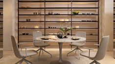 a table with four chairs around it in front of shelves filled with candles and vases