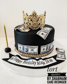 a birthday cake with money and a crown on top, sitting on a white table